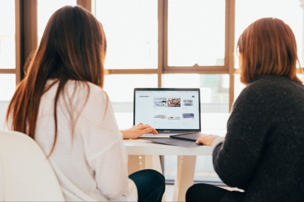 Two women browsing a webpage on a laptop
